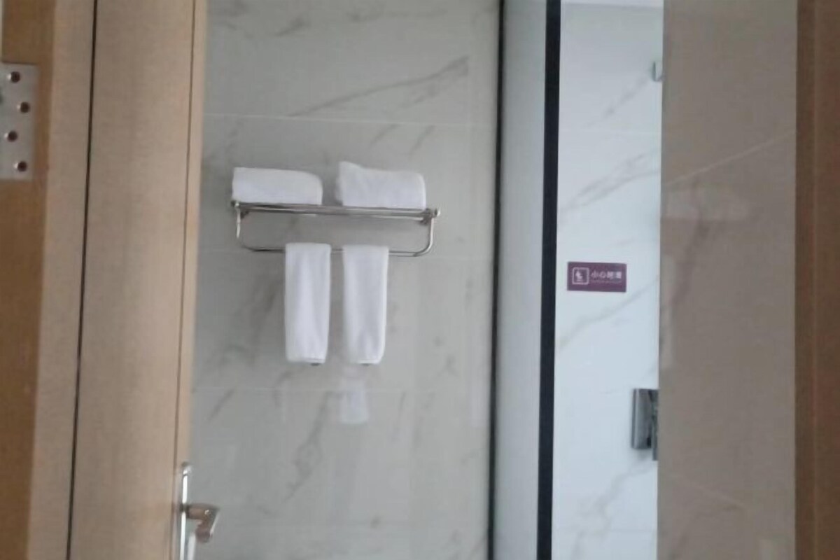 A bathroom with a marble wall, a towel rack with two white towels, and a sign indicating a handicap-accessible bathroom.