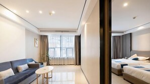 A modern hotel room with a sofa, a small table, two beds, and a large window with curtains. - Friend Yue Hotel (Zhangjiajie Town Centre Huilong Road) (Zhangjiajie)