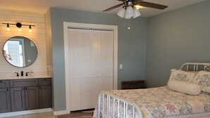 Une chambre à coucher avec un lit, un ventilateur de plafond, une armoire et un miroir.