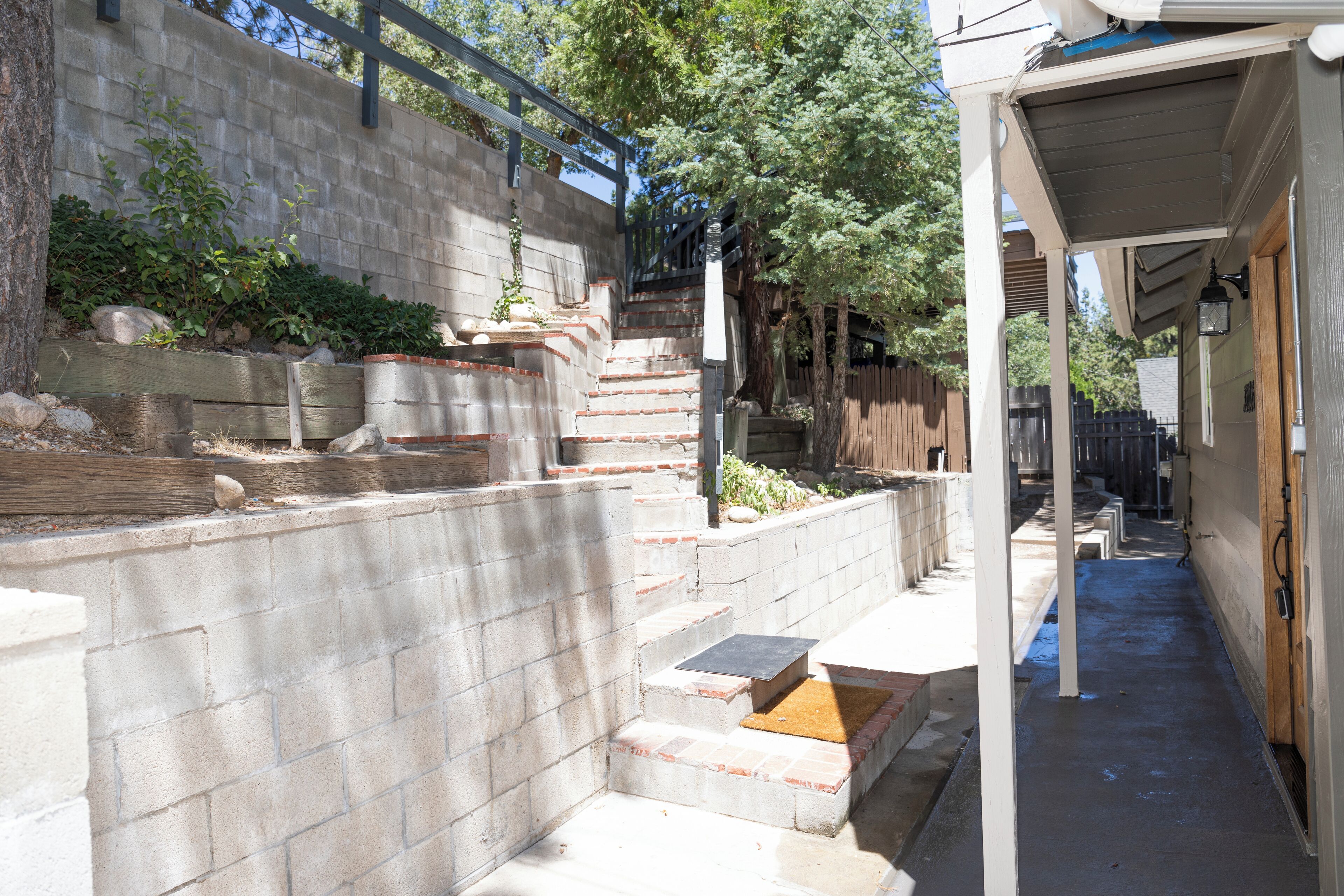 A concrete staircase leading up to a wooden deck, surrounded by a stone wall and a wooden fence.