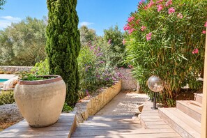 Un jardin avec une terrasse en bois, un grand pot et un objet sphérique en verre.