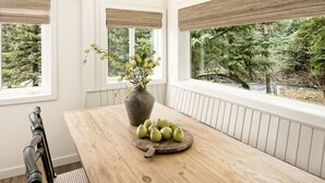 Un coin repas avec une table en bois, un vase de fleurs et un panier de fruits.