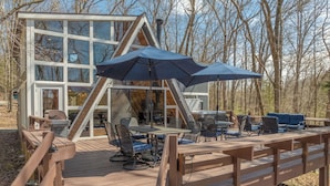 Eine Holzterrasse mit Gartenmöbeln und einem Glasgebäude im Hintergrund.