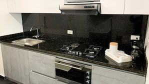 Una cocina moderna con un lavamanos de acero inoxidable, un microondas, una estufa a gas y un horno empotrado.