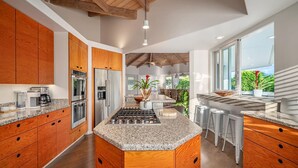 Una cocina moderna con encimeras de granito, armarios de madera y electrodomésticos de acero inoxidable, además de una isla central.
