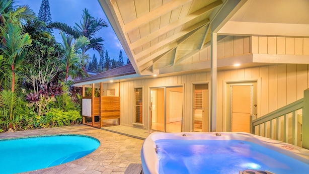 Ein Poolbereich mit Whirlpool, umgeben von üppiger tropischer Vegetation und einer Holzterrasse.