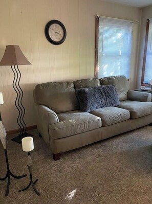 Relax in this inviting living room with a comfortable sofa, floor lamp, and wall clock.