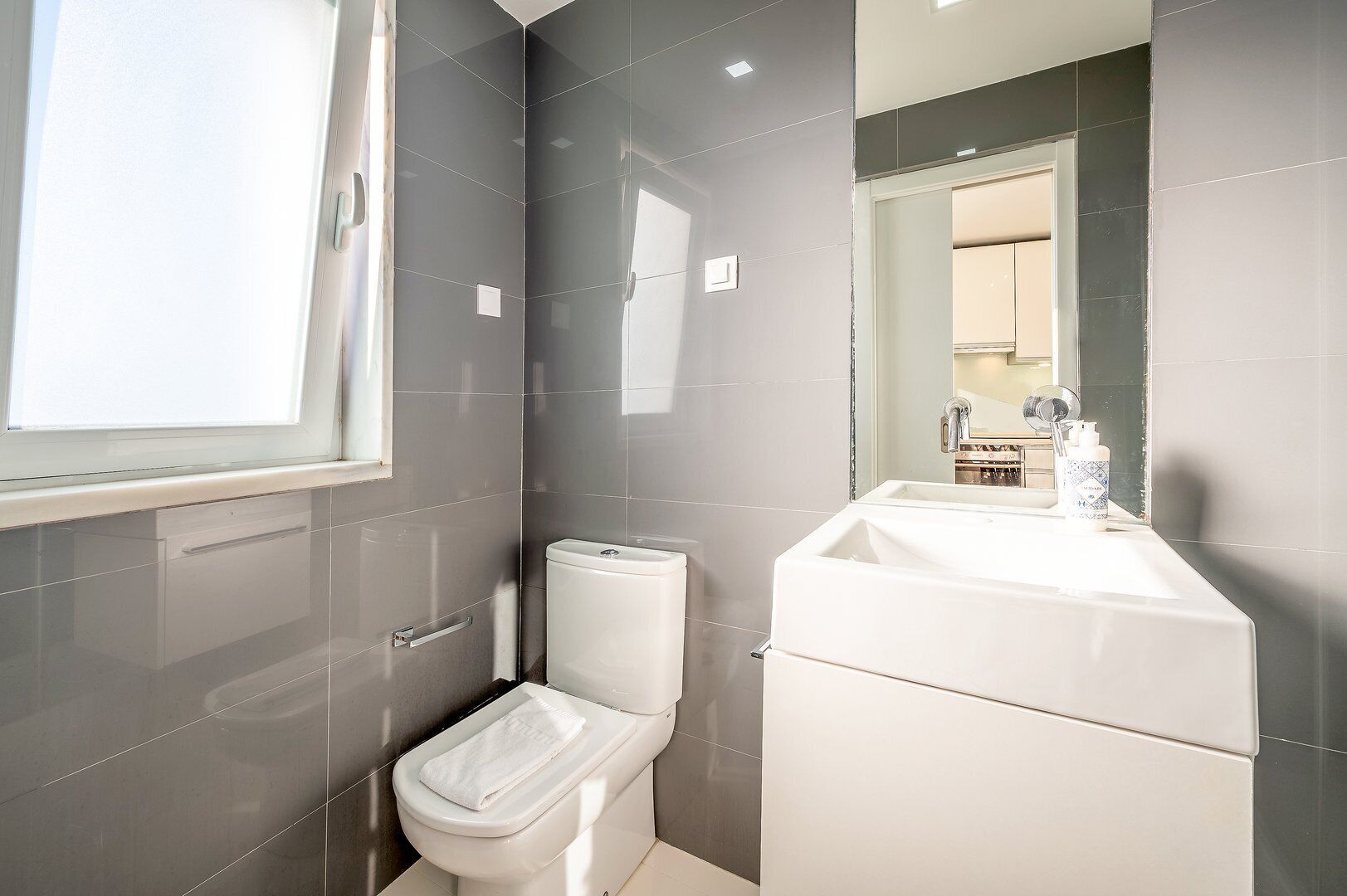 Een moderne badkamer met toilet, wastafel en spiegel.