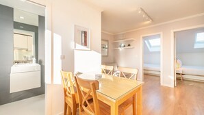 A modern apartment with a dining area, kitchen, and a cozy seating space. - GuestReady - Sunny spacious in Belém (Lisbon)