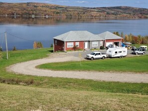 Situated on a grassy area, this property offers a parking space and overlooks a large body of water with hills in the background.
