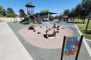 Ein Spielplatz mit Rutsche, Klettergerüsten und einem überdachten Spielbereich.