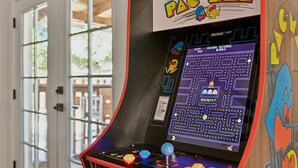 Uma máquina de arcade Pac-Man com um jogo de labirinto exibido, um indicador de pontuação e um joystick.