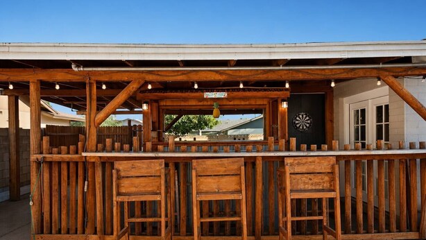 Uma área de bar ao ar livre com banquetas de madeira e um alvo de dardos.