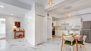 Eine moderne Küche mit weißen Schränken, einem Edelstahl-Kühlschrank und einem Essbereich mit Tisch und Stühlen.
