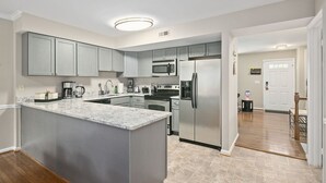 Una cocina moderna con armarios grises, electrodomésticos de acero inoxidable y encimera de mármol.