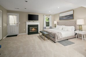 A bedroom with a fireplace, a bed, a bench, a TV, and a painting on the wall. - Finchvale: Work-Friendly, Private Yard, Near DC (Sterling)