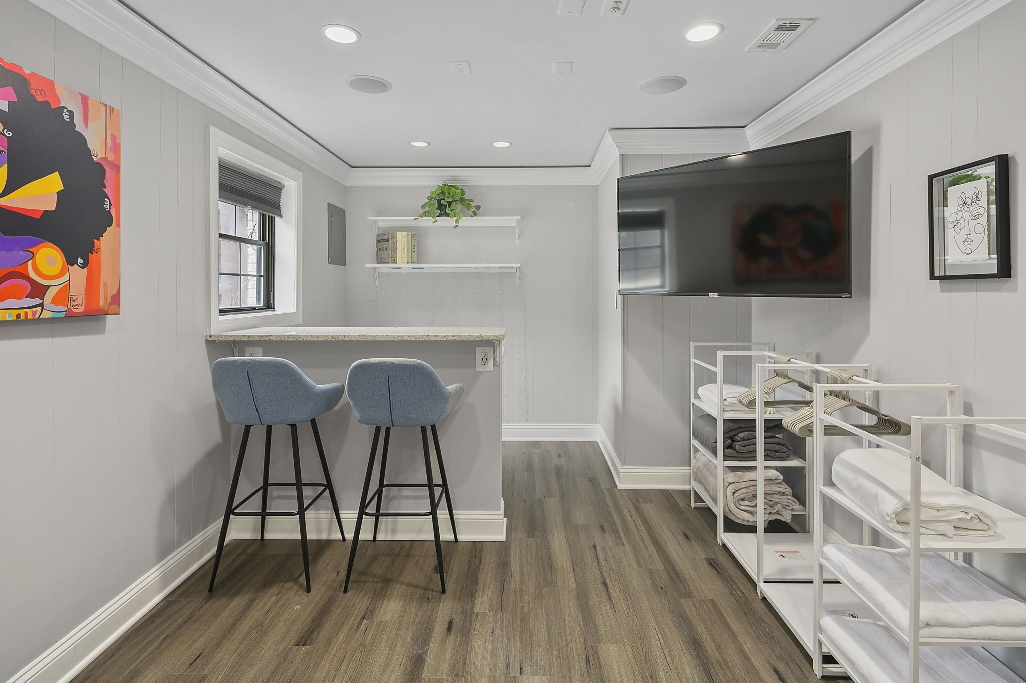 Une chambre compacte et moderne, dotée d’une kitchenette, de deux tabourets de bar, d’une télévision et d’une étagère où sont pliés les serviettes.