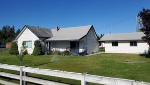 A two-story house with a front porch, a small attached garage, and a fenced yard.
