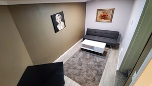 A compact living space with a sofa, a small table, and a framed picture on the wall.
