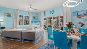 A modern living room with a sofa, dining table, and chairs. There is a large window with a view of the beach. - 3101 Spring Special Discount Book Mar 6th ~Poolside ~Heated Pool ~Hot Tub (Destin)