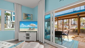 A living room with a large TV, a sofa, and a view of a beach through a sliding glass door. - 3101 Spring Special Discount Book Mar 6th ~Poolside ~Heated Pool ~Hot Tub (Destin)