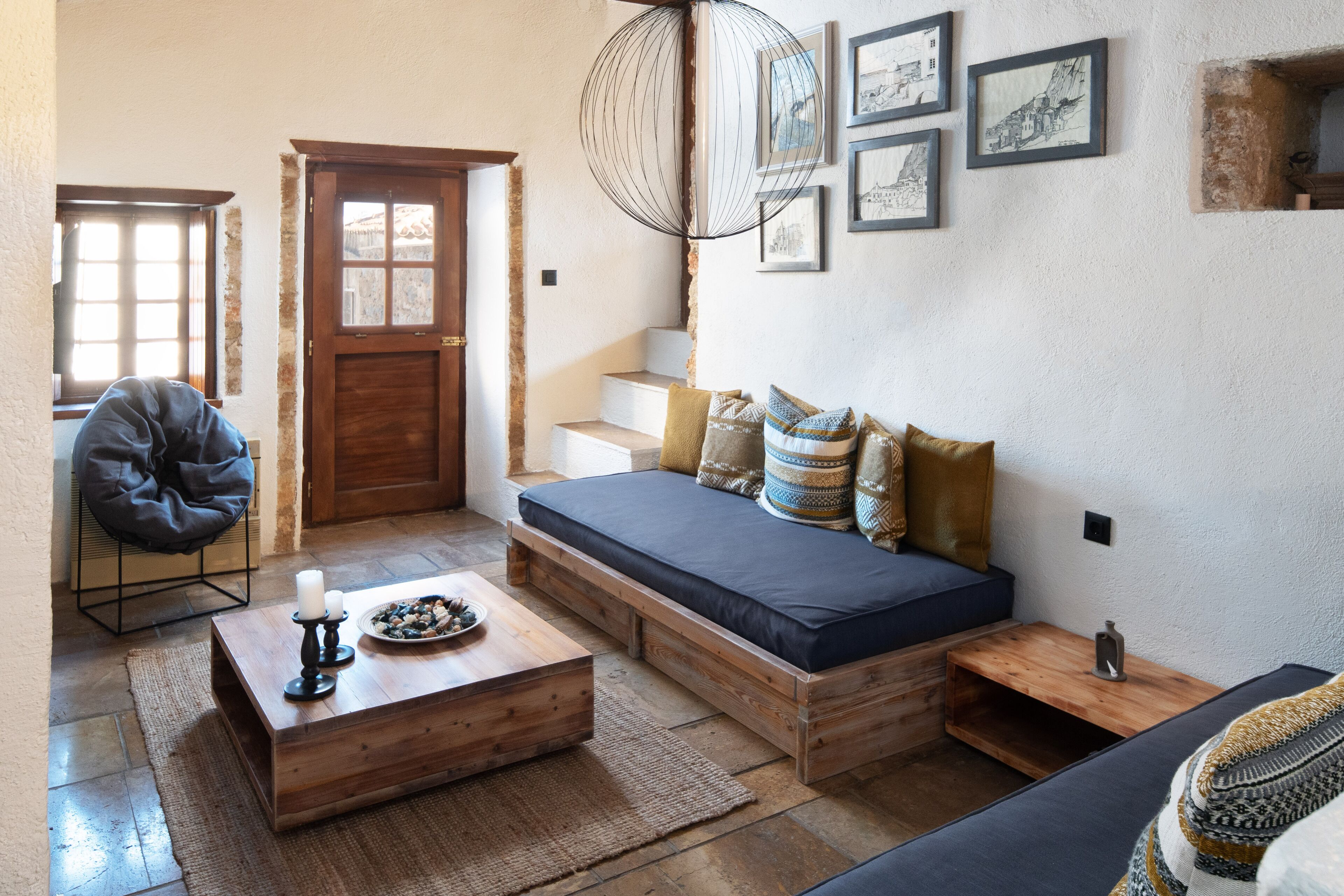 Una habitación acogedora con un sofá de madera, una mesa de comedor con velas y una silla.