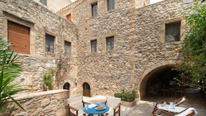 Un patio de piedra con mobiliario exterior y una pared de piedra.