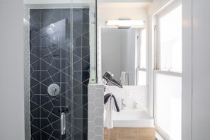 A modern bathroom with a glass-enclosed shower, a white sink, and a large mirror.