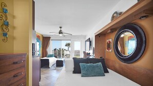 Ein Schlafzimmer mit Bett, Schminktisch, Deckenventilator, großem Spiegel und Blick ins Freie.