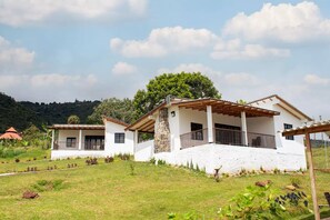 Enjoy a shaded outdoor space with a covered patio and pergola, surrounded by lush gardens and a grassy lawn.
