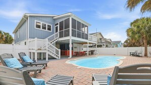 A two-story house with a pool, outdoor seating, and a covered patio area.