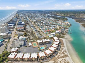 Eine Vogelperspektive eines Küstenresorts mit Strandvillen, einer Marina und einem großen Schwimmbecken.
