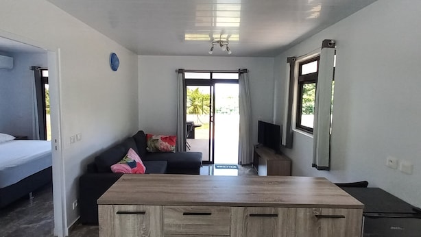 Un espacio habitable compacto con una cama, un sofá, una mesa de madera y un televisor.