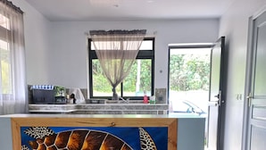 Una habitación con un gran mural de tortuga, una zona de cocina con microondas y lavamanos, y vistas a zonas verdes exteriores.