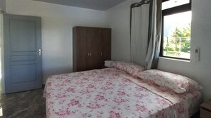 Un dormitorio con cama, armario, puerta y ventana con cortinas.