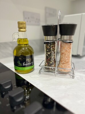 En køkkenbordplade med en flaske Truvia ekstra jomfru olivenolie og to krydderibehholdere.