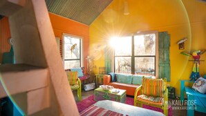 Ein farbenfroher Raum mit einem großen Fenster, einem Deckenventilator und einem Papagei auf einem Sitzstab.