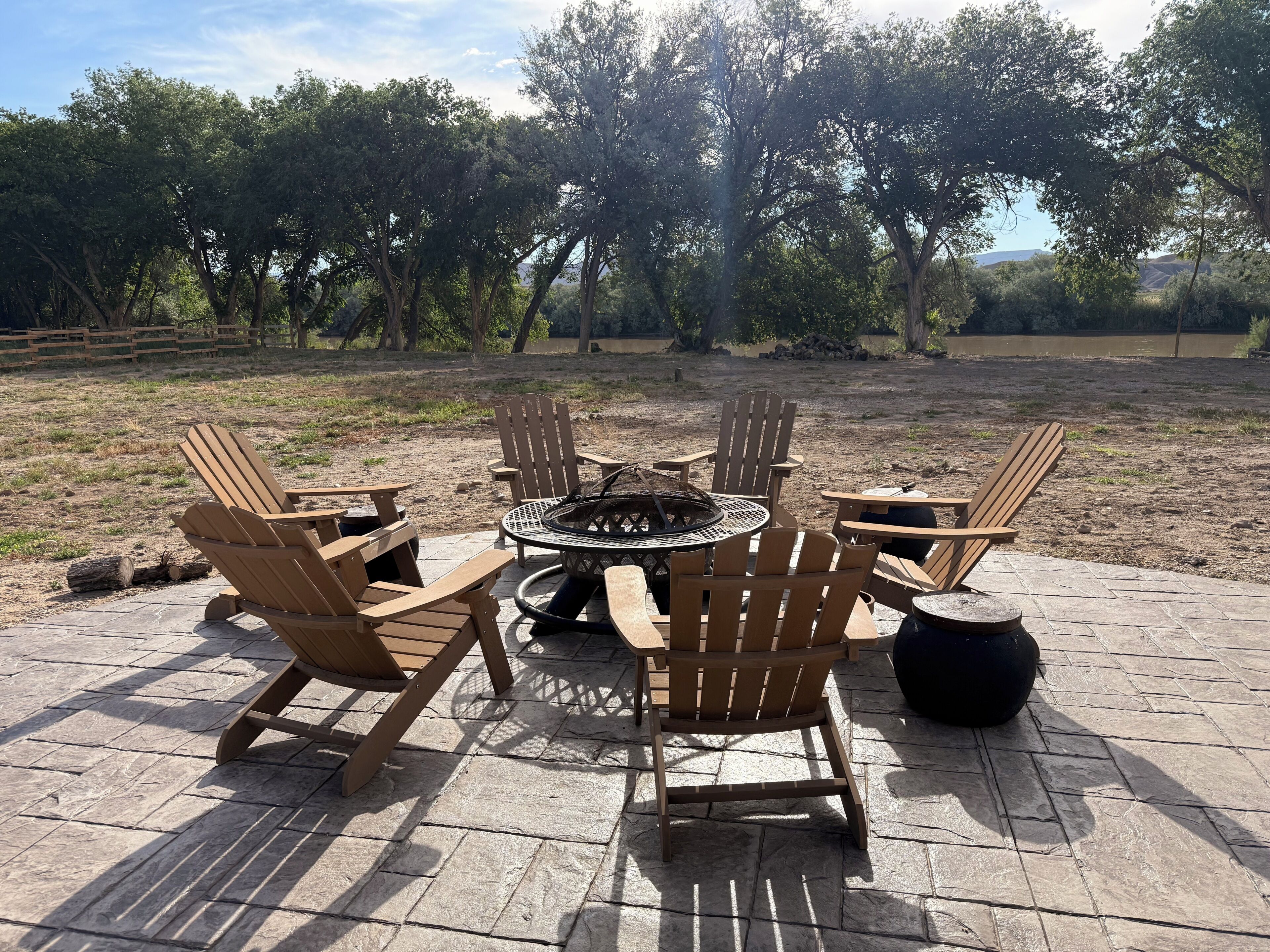 Un patio con sillas Adirondack y un pozo de fuego.
