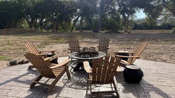 Un patio con sillas Adirondack y un pozo de fuego.