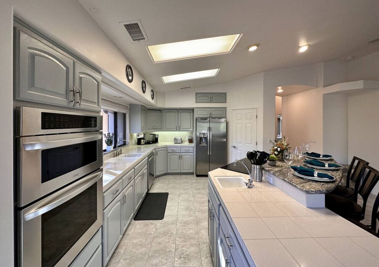 A modern kitchen with stainless steel appliances, a central island, and a dining area.