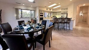 Une cuisine moderne dotée d’un îlot central, d’un coin repas avec une table ronde et d’un ventilateur de plafond.
