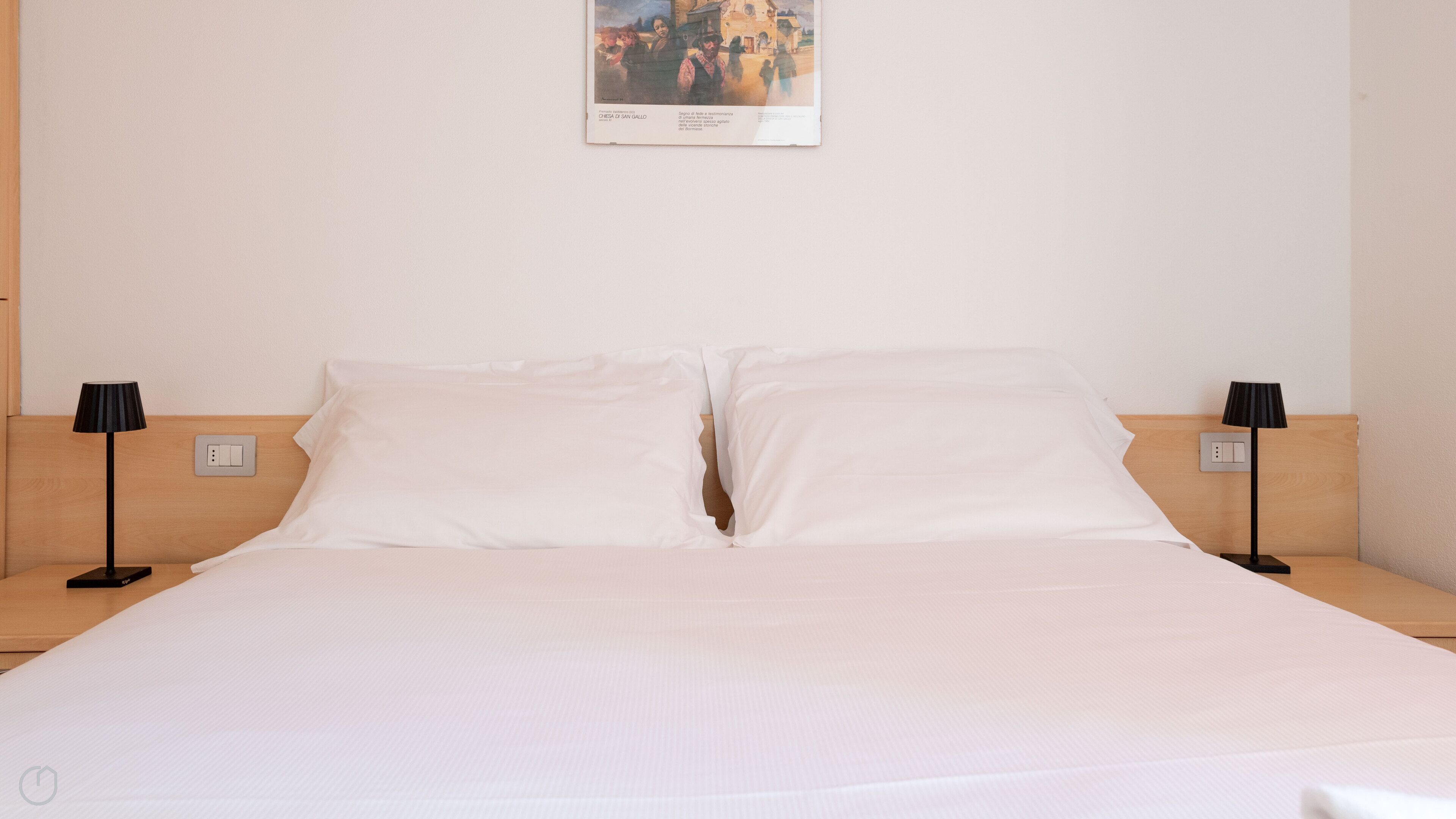 Habitació d'hotel amb un llit gran, dues taules de nit i un quadre penjat a la paret.