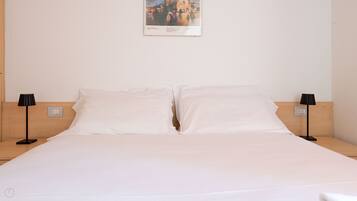 A hotel room with a large bed, two bedside tables, and a wall-mounted painting.