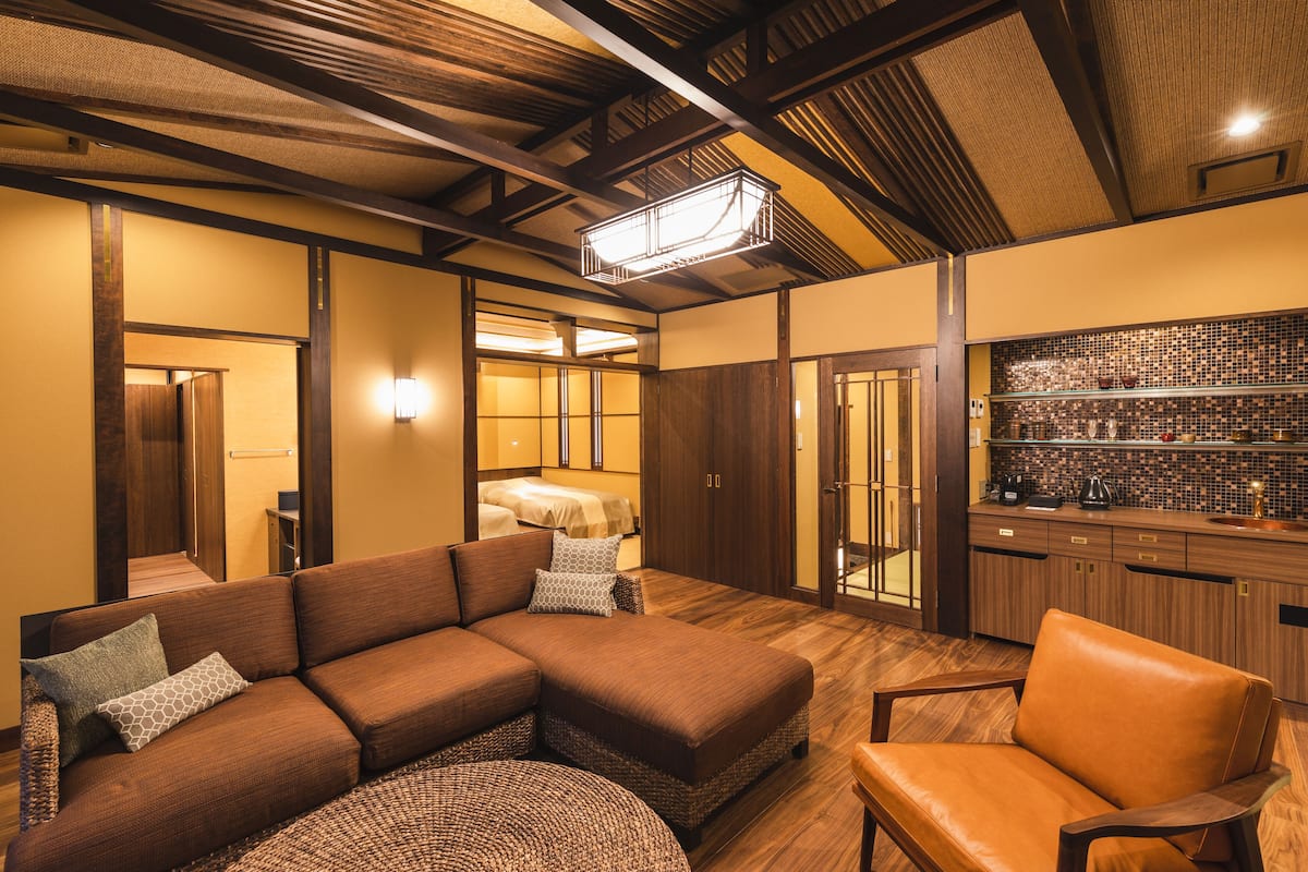 A modern living room with a sectional sofa, a leather armchair, and a woven rug.