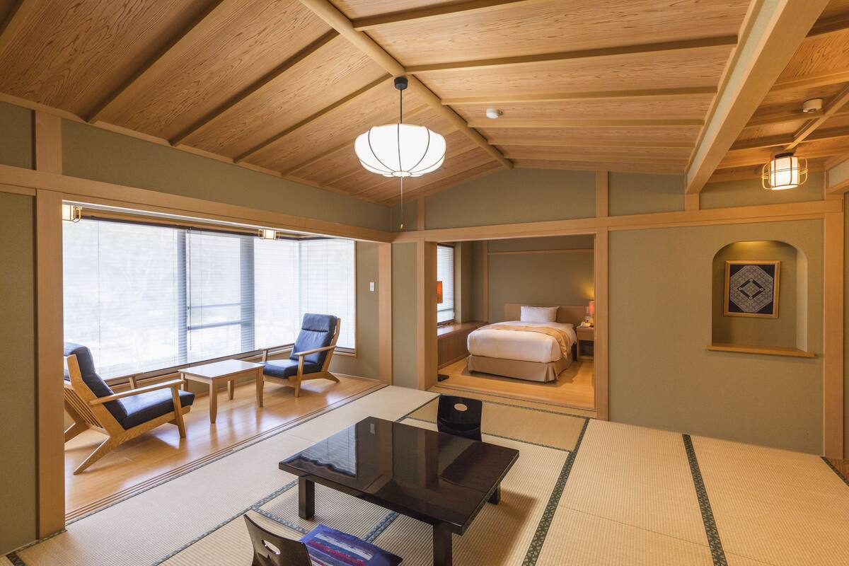 A traditional Japanese-style room with tatami flooring, a low table, and a bed.