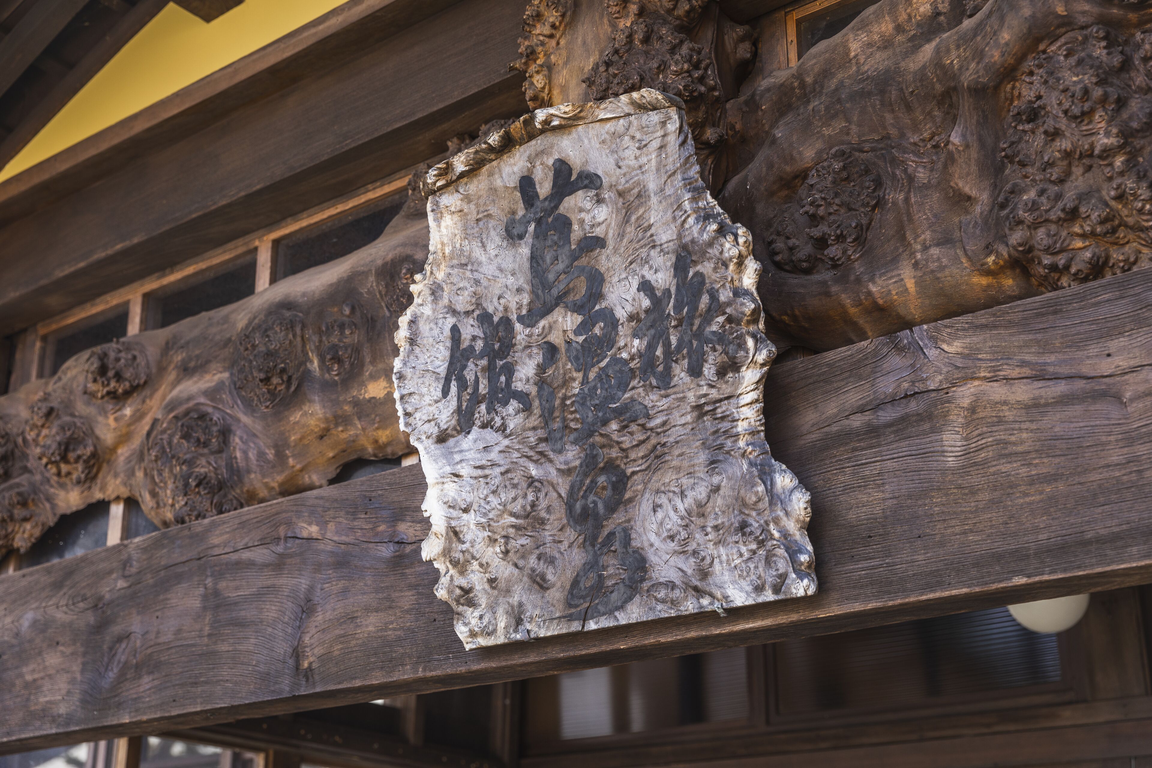 A wooden structure with carved details and a sign with characters.