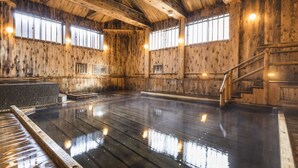 A wooden interior with a large, reflective pool area, wooden walls, and a staircase. - tsutaonsen (Towada)