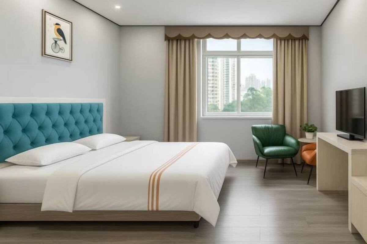 A hotel room with a large bed, a television, a desk, and a chair.