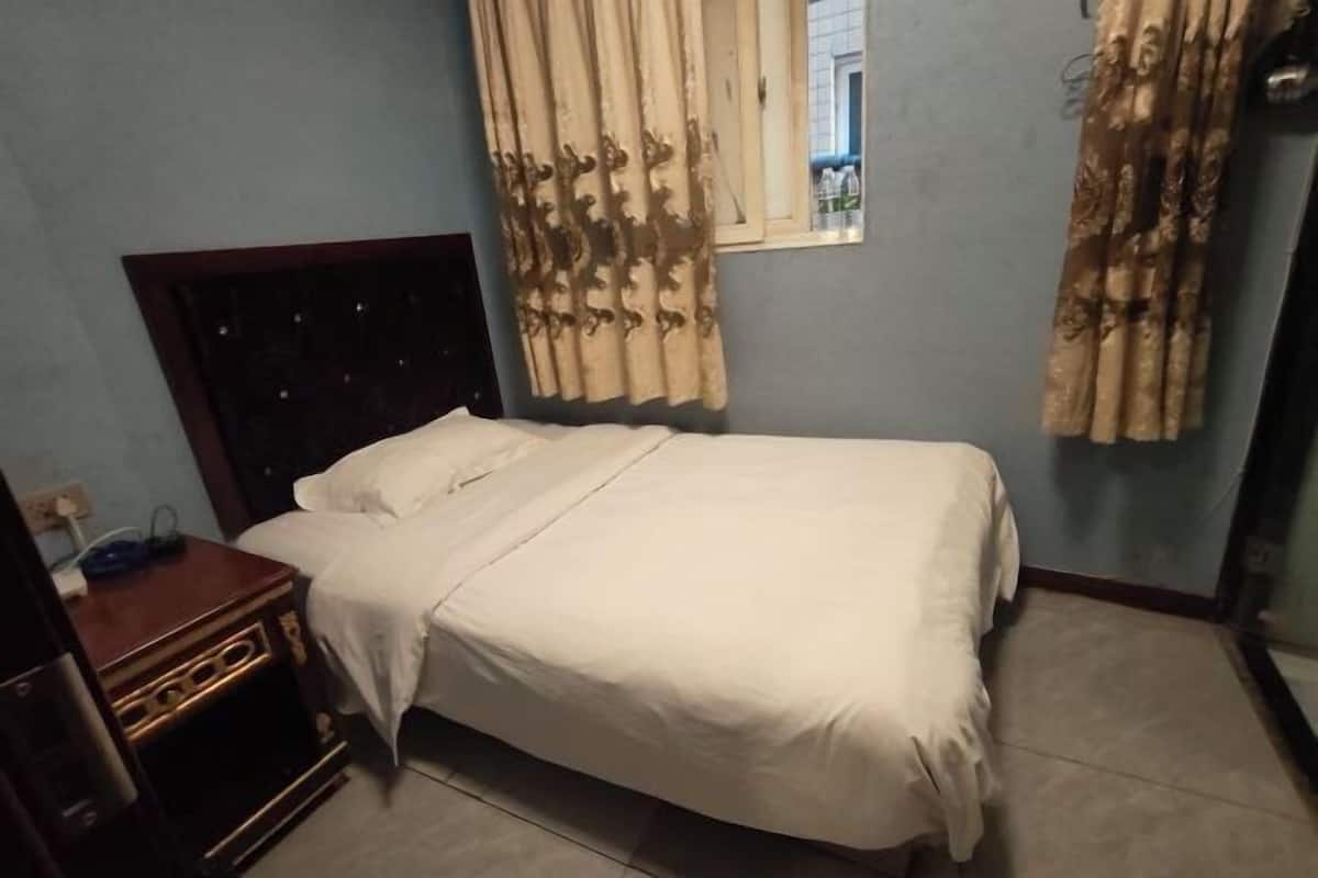 A bedroom with a bed, curtains, a nightstand, and a window.