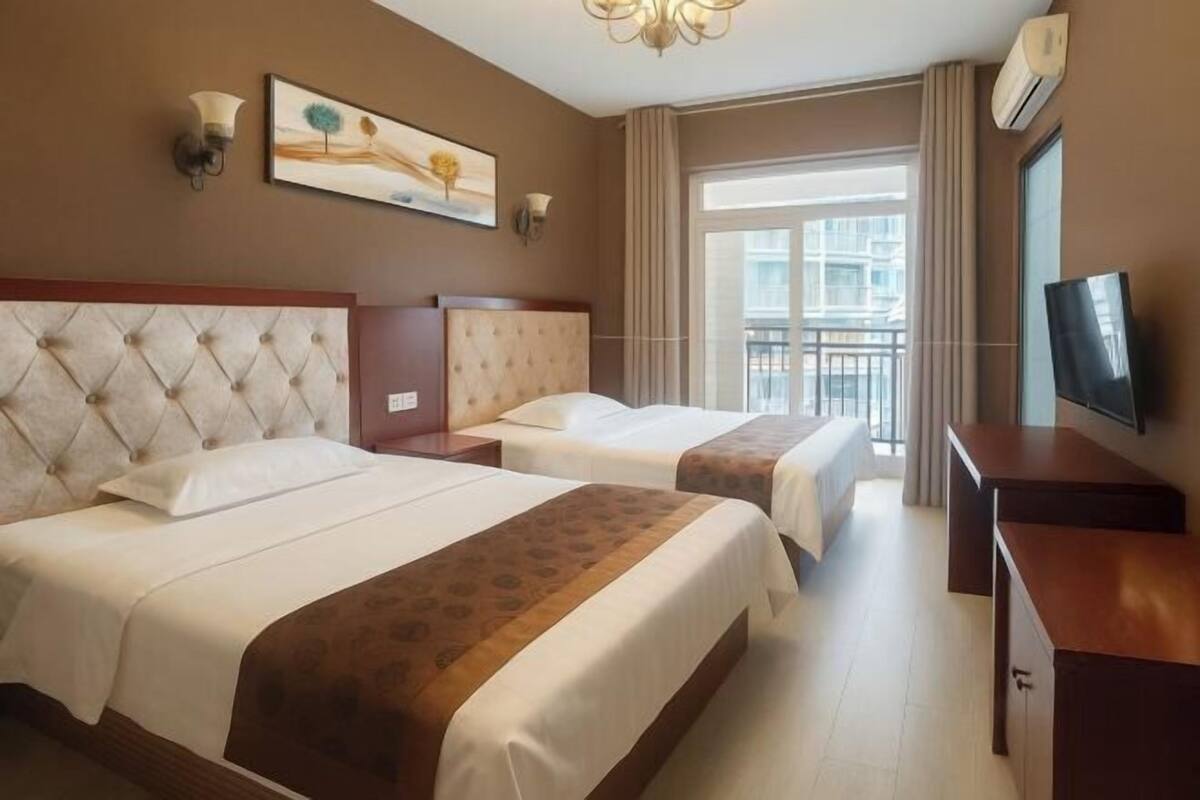 A hotel room with two beds, a TV, a painting, and a balcony with a view.